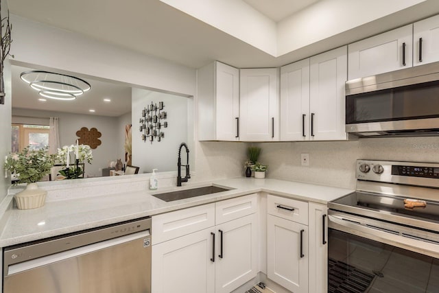 kitchen with white cabinetry, sink, stainless steel appliances, tasteful backsplash, and light stone counters