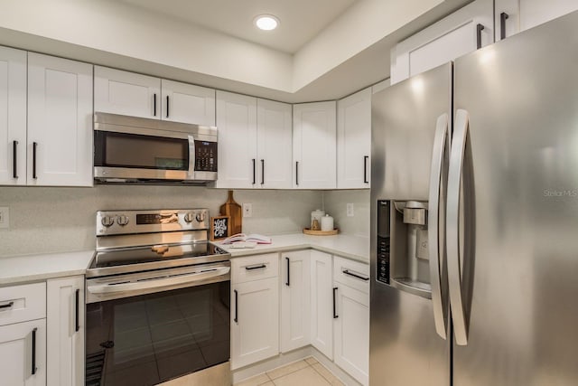 kitchen featuring backsplash, white cabinetry, stainless steel appliances, and light tile patterned floors