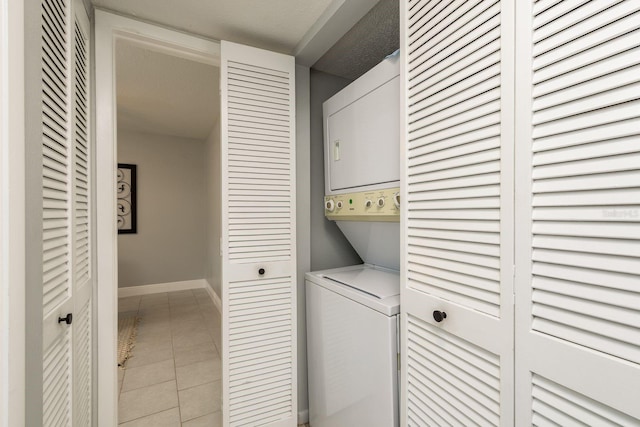 laundry area with light tile patterned floors and stacked washer / drying machine