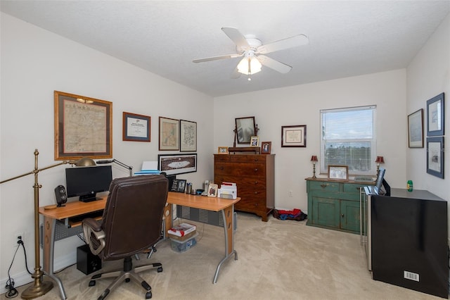 home office featuring a textured ceiling, ceiling fan, and light carpet