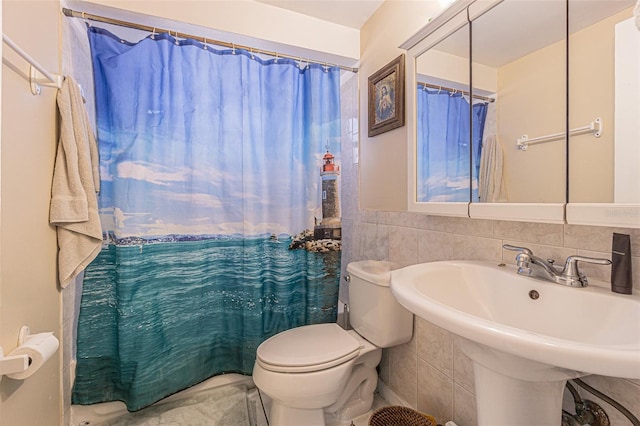 bathroom with toilet, tile walls, curtained shower, and sink