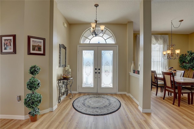 entryway featuring a chandelier, light wood-type flooring, and french doors