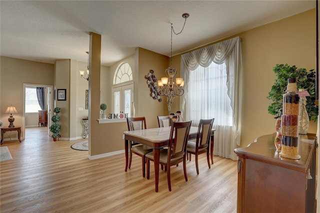 dining area featuring a textured ceiling, light hardwood / wood-style flooring, french doors, and a notable chandelier