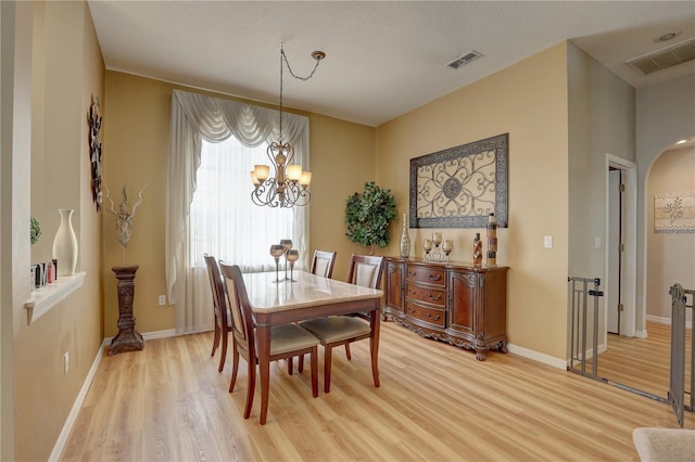 dining space featuring a chandelier, wood-type flooring, and a textured ceiling