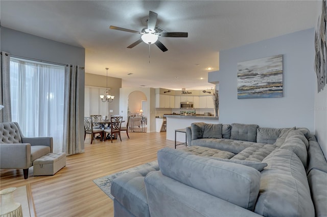 living room with light hardwood / wood-style flooring and ceiling fan with notable chandelier