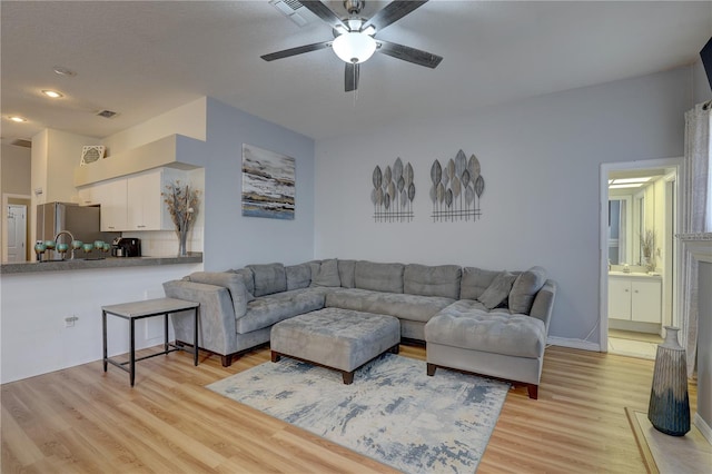 living room featuring ceiling fan, sink, and light hardwood / wood-style flooring