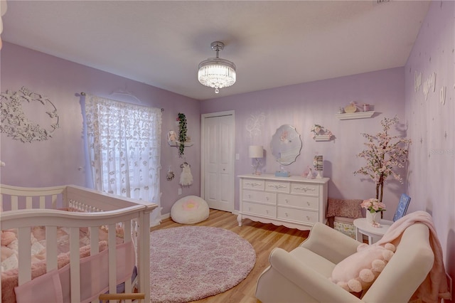 bedroom featuring a closet, light hardwood / wood-style floors, and a nursery area