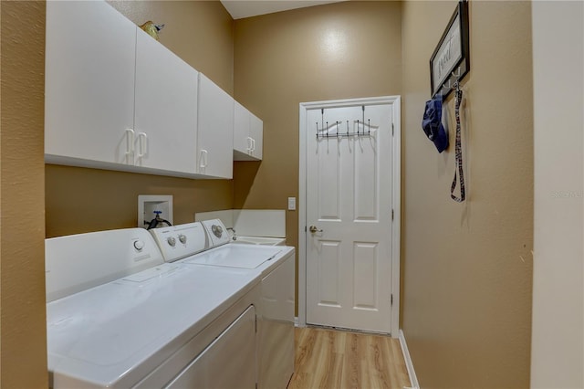 clothes washing area featuring cabinets, independent washer and dryer, and light wood-type flooring