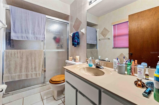 bathroom with tile patterned floors, vanity, an enclosed shower, and tile walls