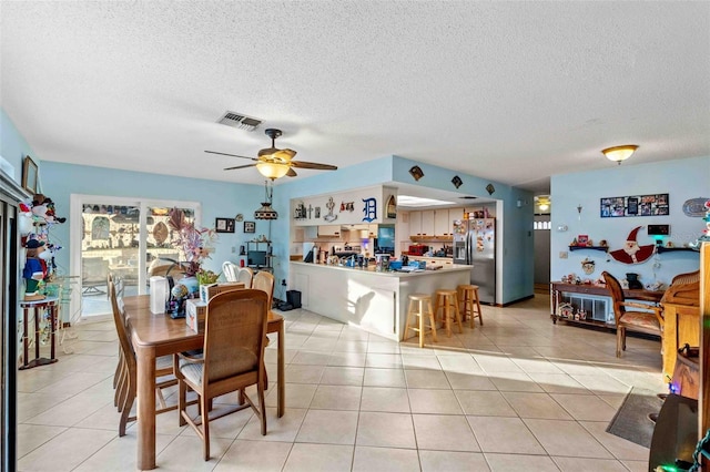 tiled dining space with ceiling fan and a textured ceiling