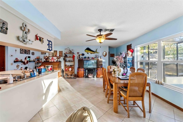 dining space with ceiling fan, sink, light tile patterned floors, and a textured ceiling