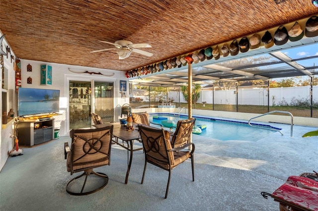 view of swimming pool featuring glass enclosure, ceiling fan, and a patio area