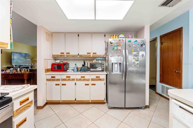 kitchen featuring white cabinetry, stainless steel fridge, dishwasher, and light tile patterned floors