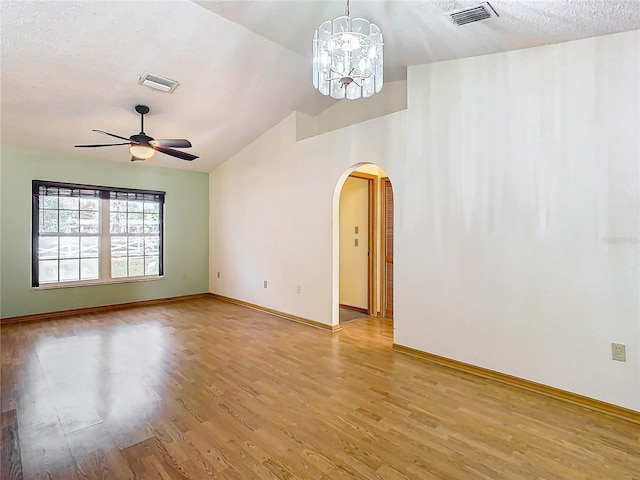 spare room with lofted ceiling, light hardwood / wood-style flooring, ceiling fan with notable chandelier, and a textured ceiling