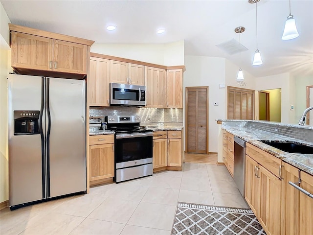 kitchen featuring light stone counters, sink, stainless steel appliances, and decorative light fixtures