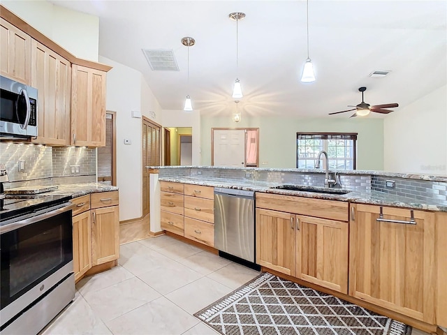 kitchen featuring sink, vaulted ceiling, decorative light fixtures, light stone counters, and stainless steel appliances