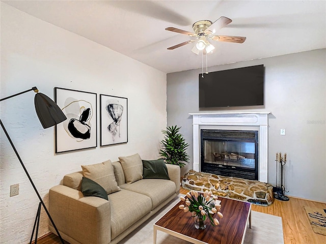 living room with ceiling fan, a fireplace, and light hardwood / wood-style floors