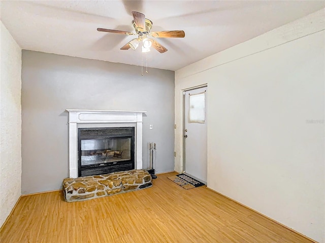 unfurnished living room with ceiling fan, a fireplace, and wood-type flooring