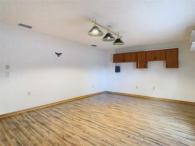 spare room featuring light wood-type flooring and a textured ceiling