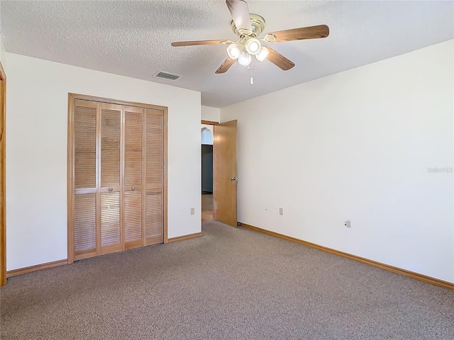 unfurnished bedroom featuring ceiling fan, a closet, carpet, and a textured ceiling