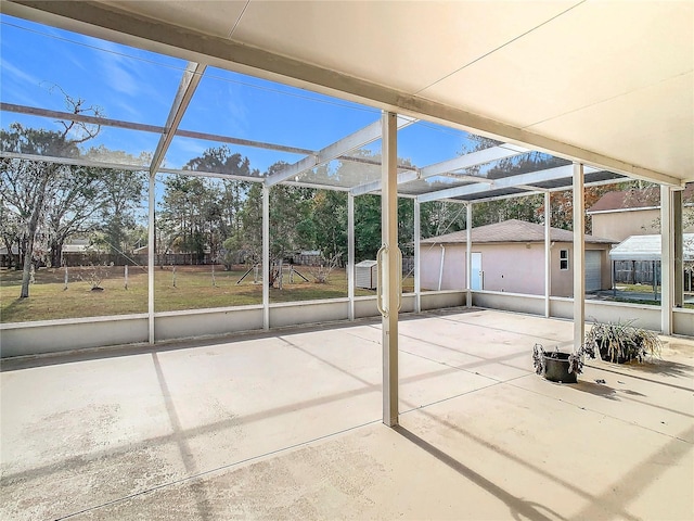 view of patio with a shed and glass enclosure