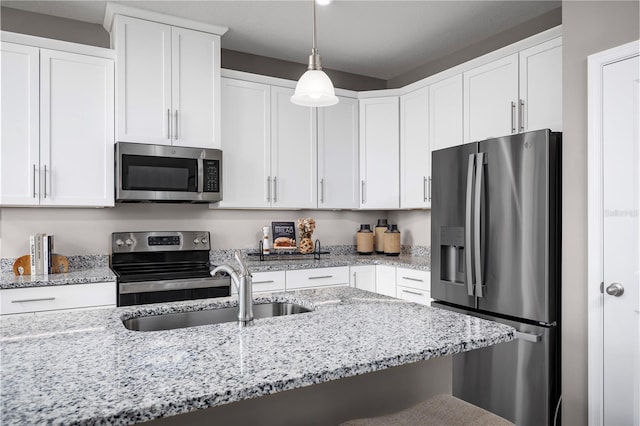 kitchen featuring sink, light stone countertops, decorative light fixtures, white cabinetry, and stainless steel appliances