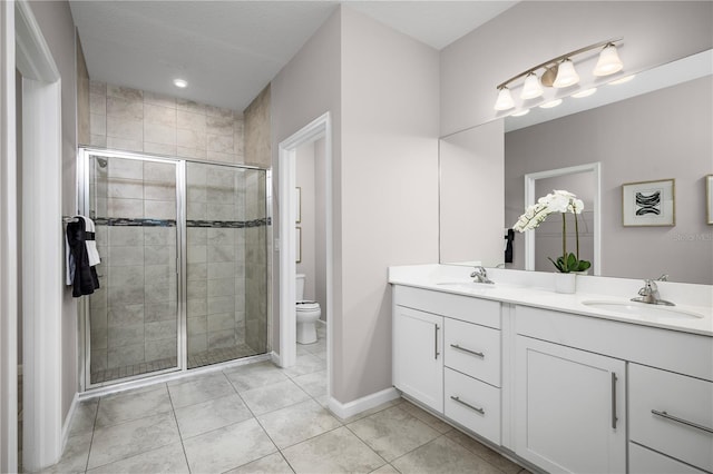 bathroom with tile patterned floors, a shower with door, vanity, and toilet