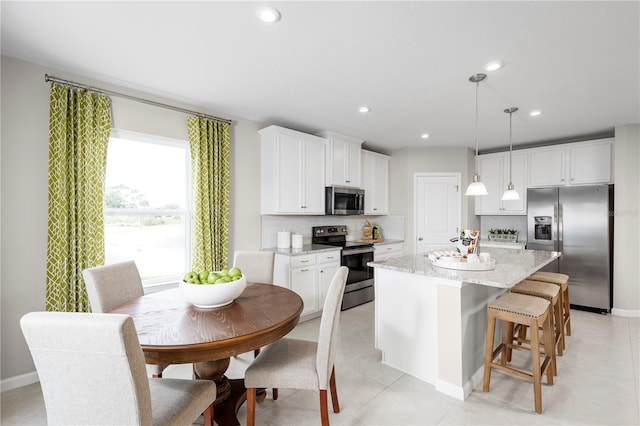 kitchen featuring white cabinets, decorative light fixtures, a kitchen island, and appliances with stainless steel finishes