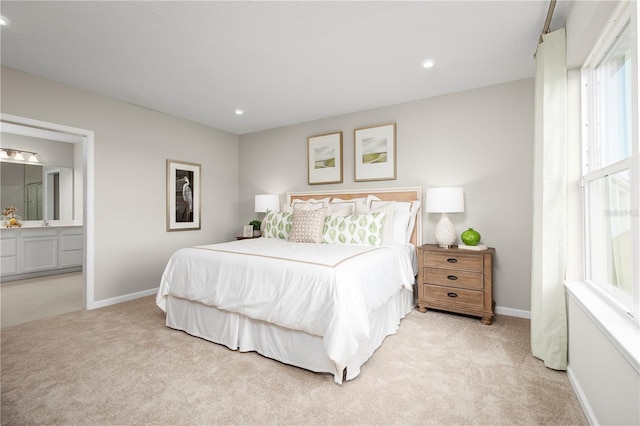 bedroom with light colored carpet and connected bathroom