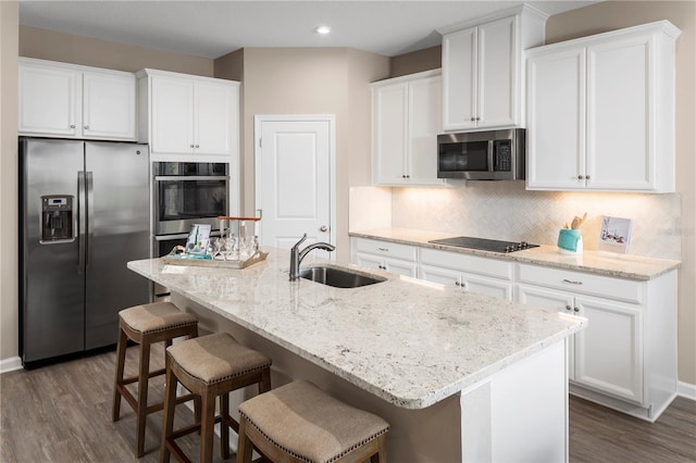 kitchen featuring dark hardwood / wood-style flooring, sink, stainless steel appliances, and an island with sink