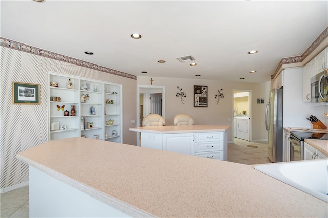 kitchen with white cabinetry, a kitchen island, separate washer and dryer, and stainless steel appliances