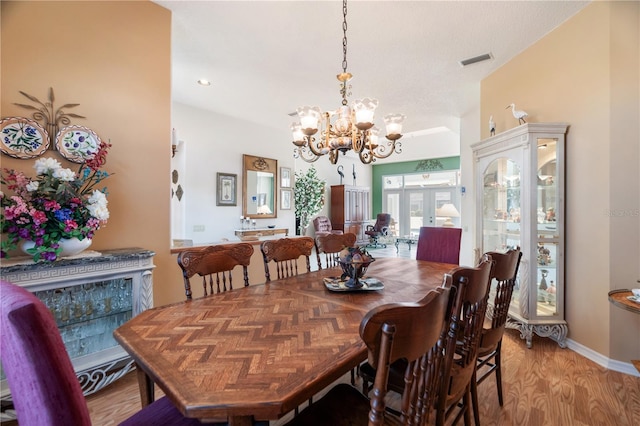 dining room with a chandelier, french doors, and light wood-type flooring