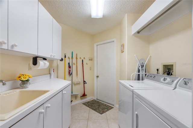 laundry room with cabinets, a textured ceiling, washer and clothes dryer, sink, and light tile patterned flooring