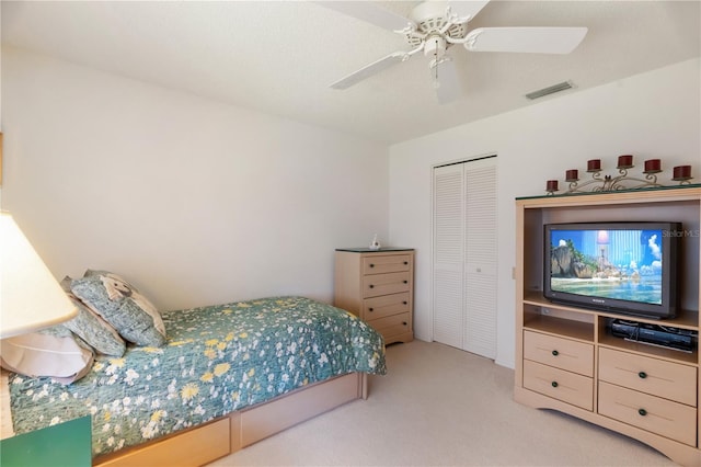 bedroom with ceiling fan, a closet, and light colored carpet