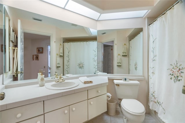 bathroom with tile patterned floors, vanity, toilet, and a skylight