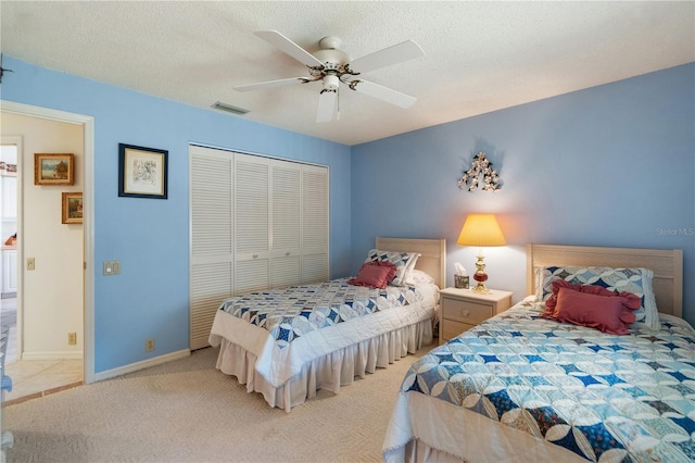 bedroom featuring a textured ceiling, a closet, ceiling fan, and light colored carpet