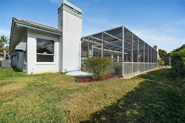 back of house with a yard, central AC unit, and a lanai