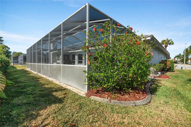 view of home's exterior featuring a yard and glass enclosure