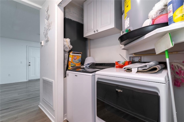 clothes washing area with hardwood / wood-style flooring, cabinets, and independent washer and dryer