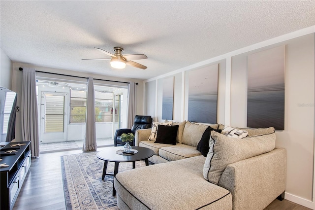 living room with ceiling fan, dark wood-type flooring, and a textured ceiling