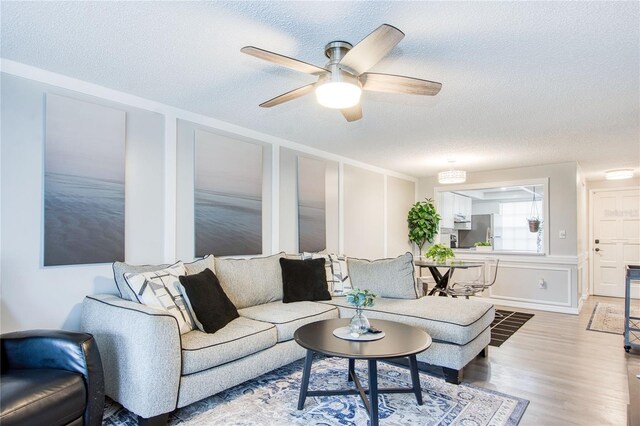 living room with ceiling fan, wood-type flooring, and a textured ceiling