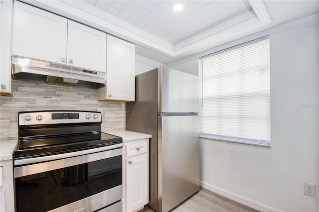 kitchen with decorative backsplash, white cabinets, stainless steel appliances, and light hardwood / wood-style floors