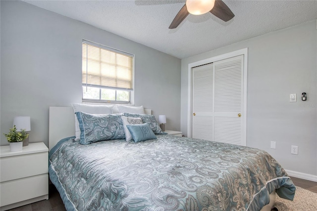 bedroom with a textured ceiling, ceiling fan, dark wood-type flooring, and a closet