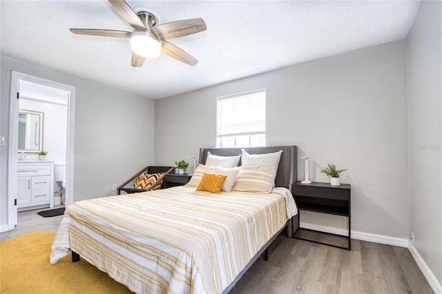 bedroom featuring ensuite bath, ceiling fan, light hardwood / wood-style floors, and a textured ceiling