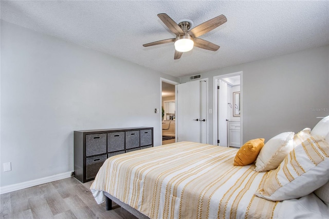 bedroom featuring ensuite bath, ceiling fan, light hardwood / wood-style flooring, and a textured ceiling