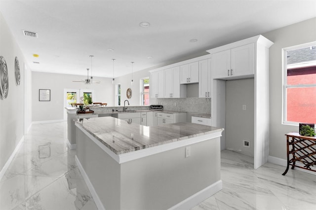 kitchen with kitchen peninsula, ceiling fan, sink, a center island, and white cabinetry