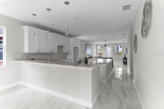 kitchen featuring kitchen peninsula, tasteful backsplash, ceiling fan, pendant lighting, and white cabinetry