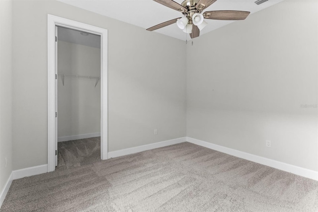 unfurnished bedroom with carpet, ceiling fan, a walk in closet, and a closet