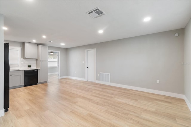 kitchen featuring decorative backsplash, light hardwood / wood-style floors, gray cabinetry, and black appliances