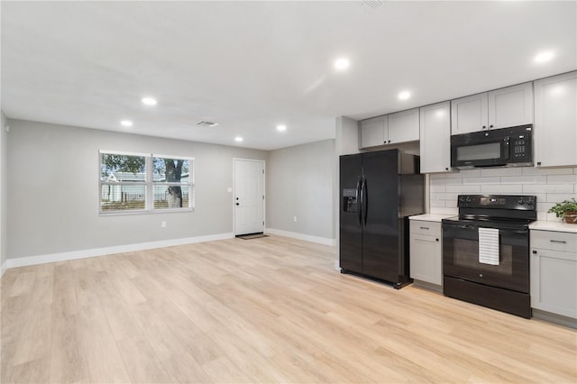 kitchen featuring decorative backsplash, light hardwood / wood-style floors, gray cabinets, and black appliances